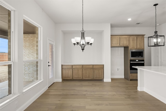 unfurnished dining area with a chandelier and light wood-type flooring