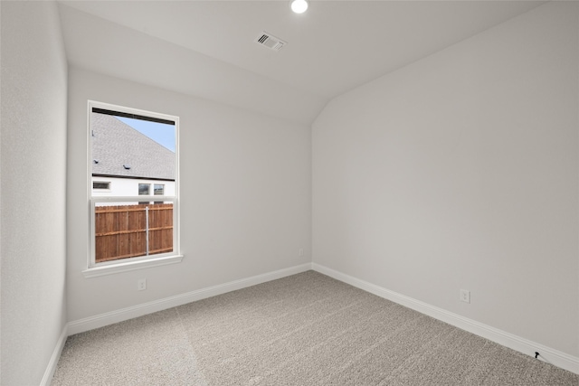 carpeted spare room with vaulted ceiling