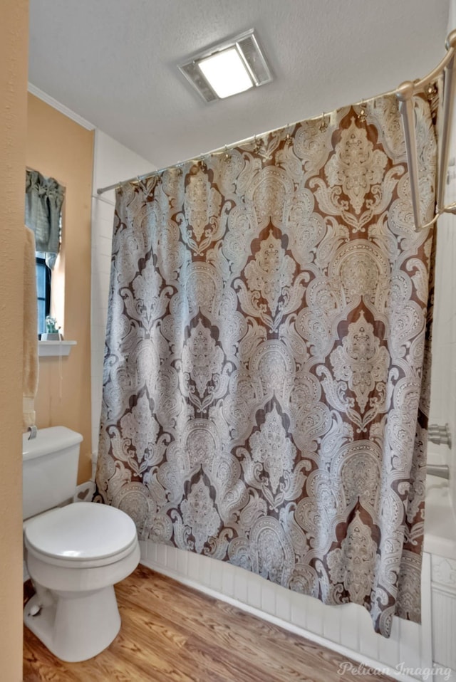 bathroom featuring shower / bath combination with curtain, hardwood / wood-style flooring, and toilet