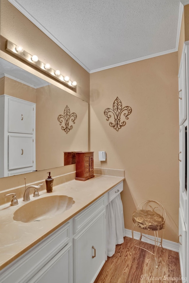 bathroom with hardwood / wood-style floors, vanity, a textured ceiling, and crown molding