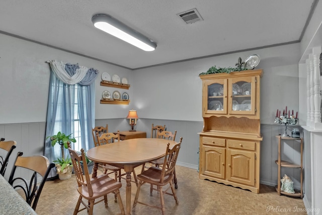 dining area with a textured ceiling and wooden walls