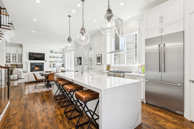 kitchen featuring a kitchen bar, white cabinetry, a large island with sink, and built in refrigerator