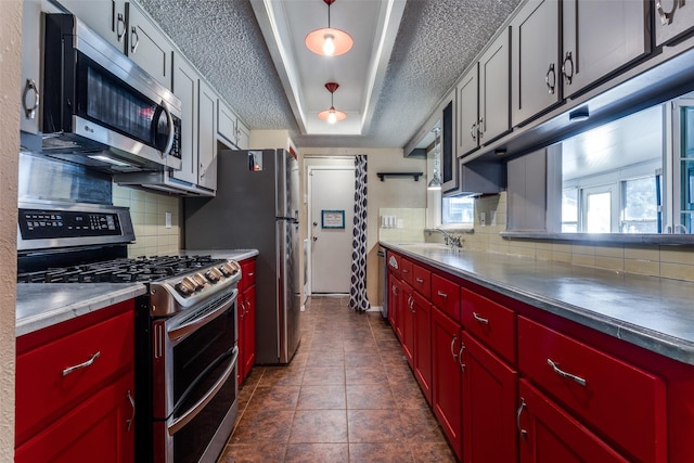 kitchen with appliances with stainless steel finishes, sink, dark tile patterned flooring, and decorative backsplash