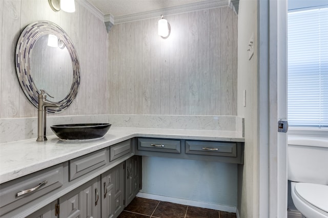 bathroom featuring a textured ceiling, toilet, a wealth of natural light, and crown molding