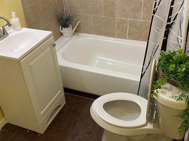 bathroom featuring a bath, vanity, wood-type flooring, and toilet