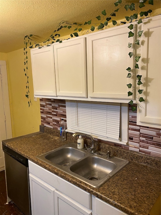 kitchen featuring tasteful backsplash, stainless steel dishwasher, a textured ceiling, sink, and white cabinetry