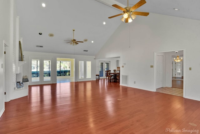 unfurnished living room with hardwood / wood-style floors, high vaulted ceiling, french doors, a brick fireplace, and ceiling fan