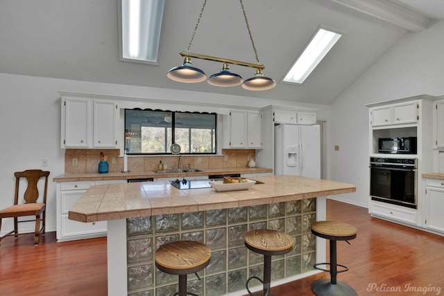 kitchen with white cabinets, a kitchen breakfast bar, pendant lighting, and black appliances