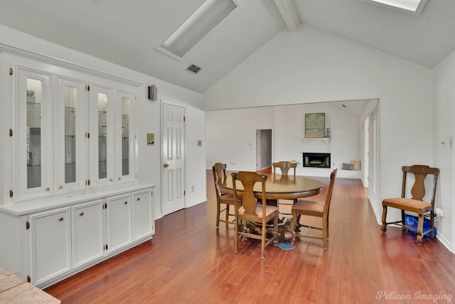 dining space with light hardwood / wood-style flooring, beamed ceiling, and high vaulted ceiling