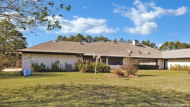 rear view of property featuring a lawn and central AC