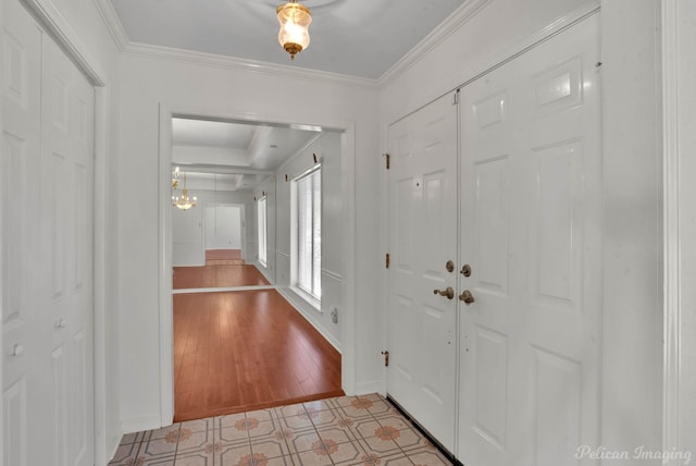 foyer with light wood-type flooring, ornamental molding, and a chandelier