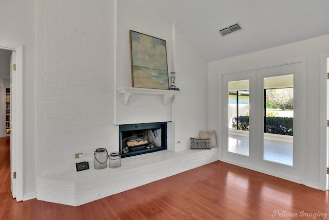 unfurnished living room with a fireplace, hardwood / wood-style floors, and lofted ceiling