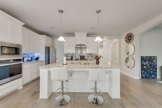 kitchen featuring light hardwood / wood-style flooring, white cabinets, stainless steel appliances, and decorative light fixtures