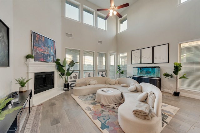 living room with a high ceiling, light hardwood / wood-style floors, and ceiling fan