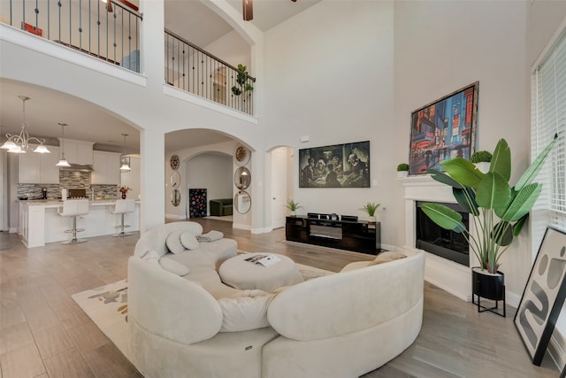 living room with light hardwood / wood-style flooring, a high ceiling, and a notable chandelier