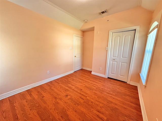 unfurnished bedroom featuring vaulted ceiling, multiple windows, a closet, and light hardwood / wood-style flooring