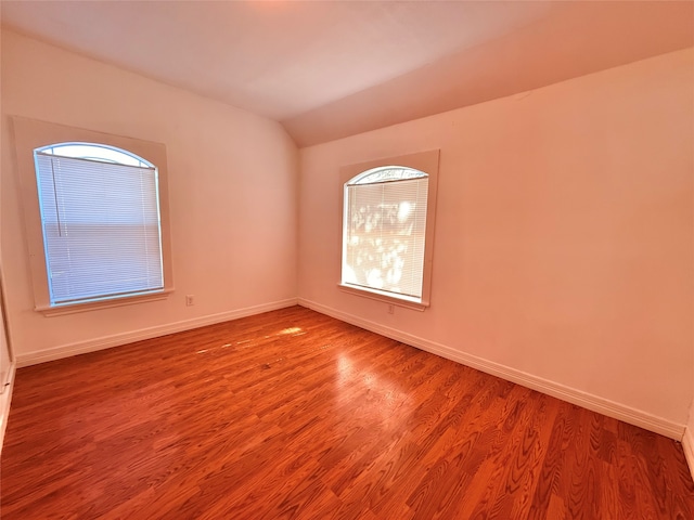 spare room with vaulted ceiling and hardwood / wood-style flooring