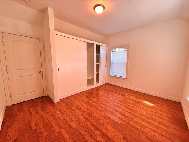 unfurnished bedroom featuring hardwood / wood-style floors and vaulted ceiling