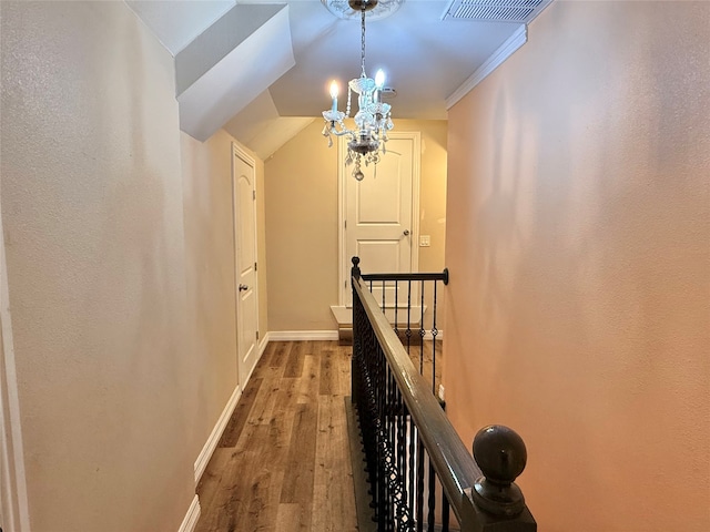 hall featuring hardwood / wood-style floors, an inviting chandelier, and ornamental molding