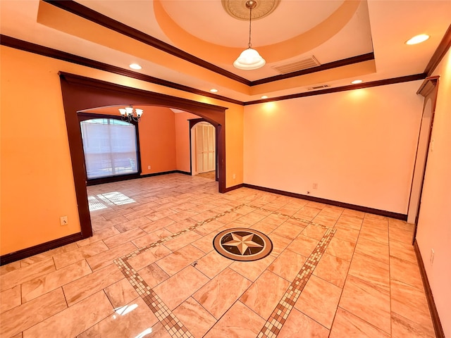 empty room featuring a chandelier, a raised ceiling, and crown molding