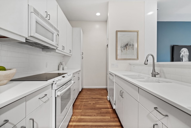 kitchen featuring hardwood / wood-style floors, white appliances, sink, decorative backsplash, and white cabinetry