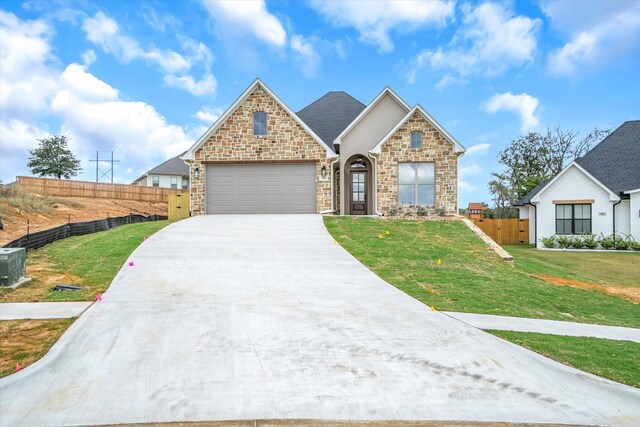 view of front facade featuring a front lawn, central AC unit, and a garage