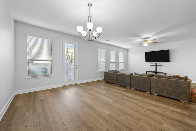 unfurnished living room with ceiling fan with notable chandelier and light wood-type flooring