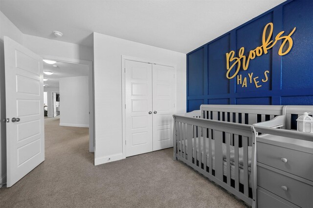 carpeted bedroom with a crib and a closet