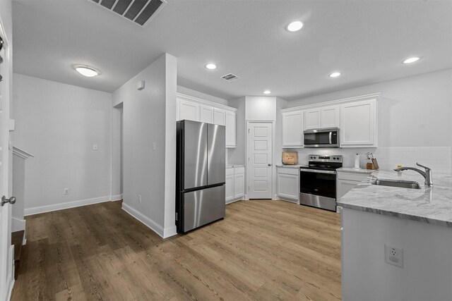 kitchen with light hardwood / wood-style floors, white cabinetry, and appliances with stainless steel finishes