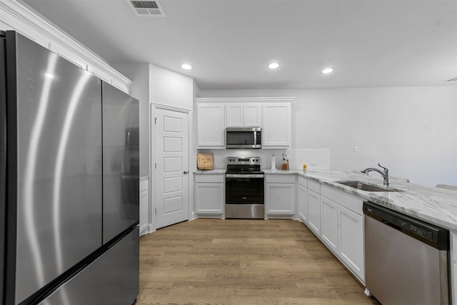 kitchen featuring white cabinetry, sink, stainless steel appliances, and light wood-type flooring