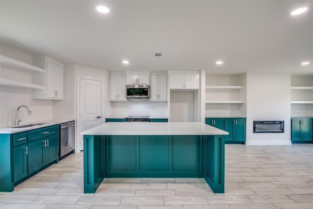 kitchen with blue cabinetry, appliances with stainless steel finishes, white cabinetry, and sink