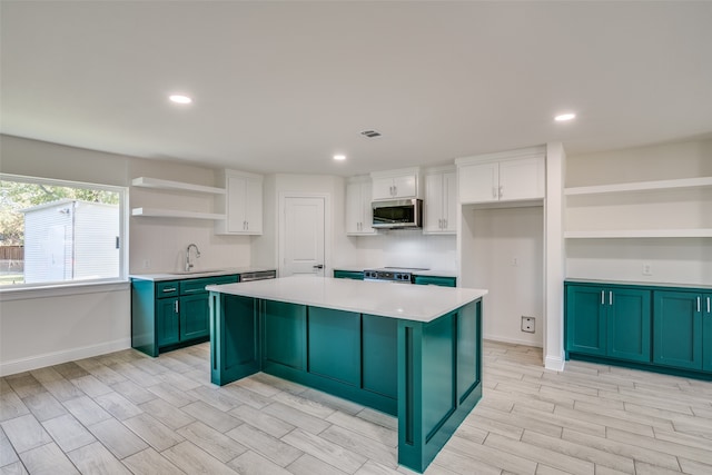 kitchen featuring white cabinetry, sink, a center island, and light wood-type flooring