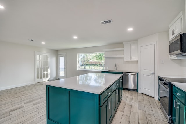 kitchen with light wood-type flooring, white cabinetry, and stainless steel appliances