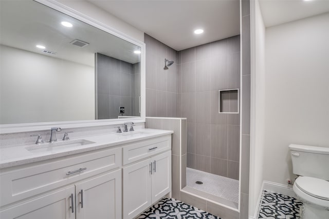 bathroom with a tile shower, vanity, toilet, and tile patterned floors