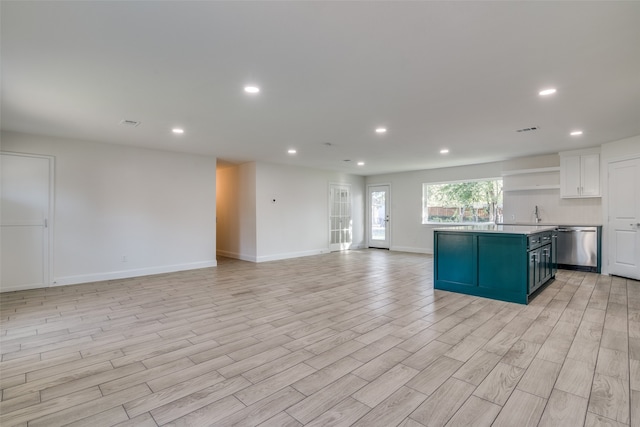 kitchen with white cabinets, a center island, light hardwood / wood-style floors, and stainless steel dishwasher