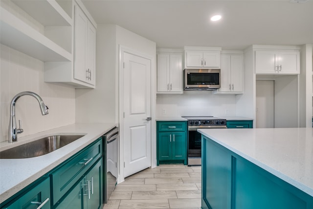 kitchen with sink, white cabinets, stainless steel appliances, and light hardwood / wood-style floors