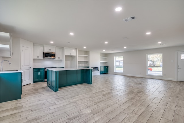 kitchen with white cabinetry, blue cabinets, stainless steel appliances, and light hardwood / wood-style floors