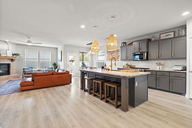 kitchen with pendant lighting, stainless steel appliances, a kitchen island with sink, and a healthy amount of sunlight