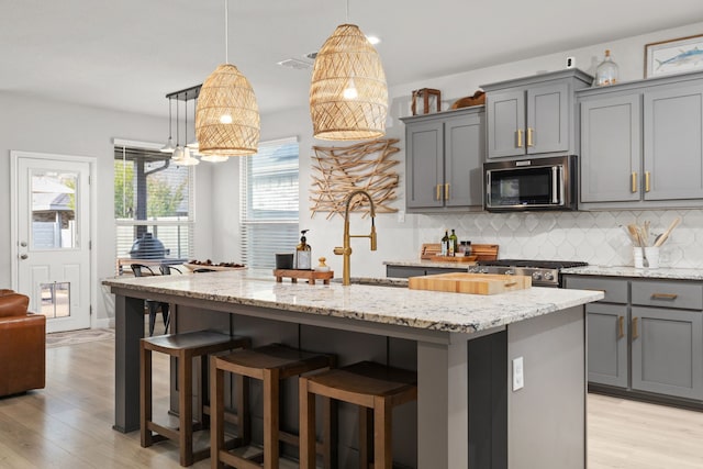 kitchen featuring a kitchen island with sink, plenty of natural light, light hardwood / wood-style floors, and appliances with stainless steel finishes