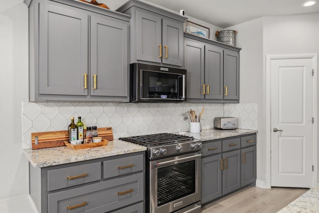 kitchen with gray cabinets, stainless steel appliances, and light hardwood / wood-style flooring