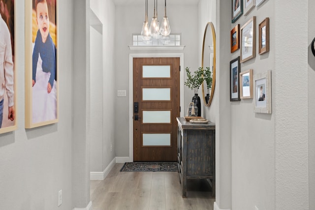 foyer featuring light wood-type flooring and a chandelier