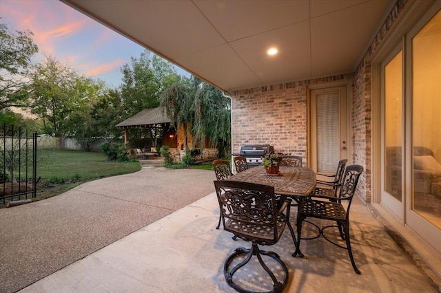 patio terrace at dusk featuring a gazebo and a yard