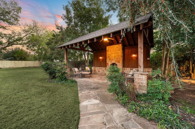 patio terrace at dusk featuring a lawn and an outdoor fire pit