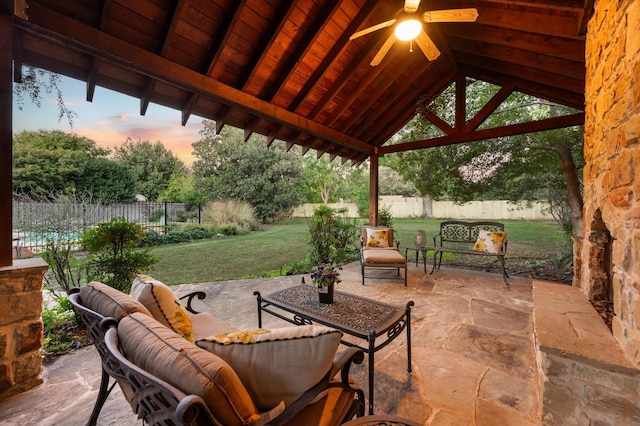 patio terrace at dusk with ceiling fan, a yard, a gazebo, and outdoor lounge area