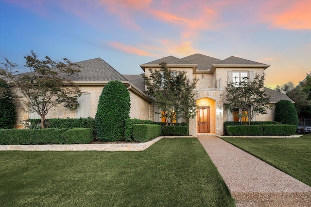 french country style house with a balcony and a lawn