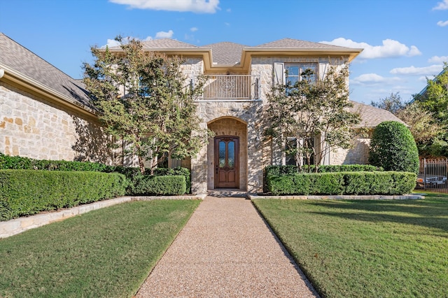 view of front of house featuring a balcony and a front yard