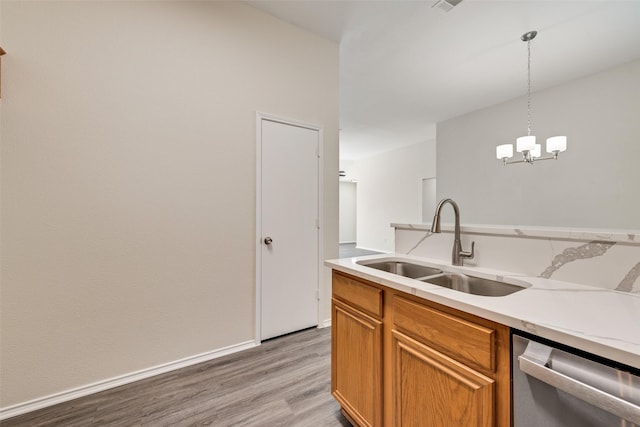 kitchen with pendant lighting, sink, dishwasher, an inviting chandelier, and light hardwood / wood-style floors