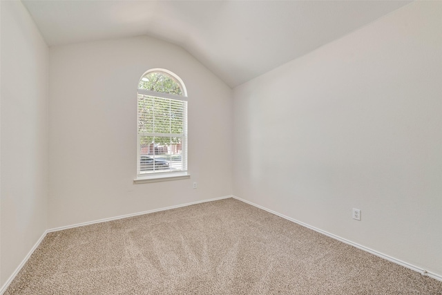 carpeted empty room featuring vaulted ceiling