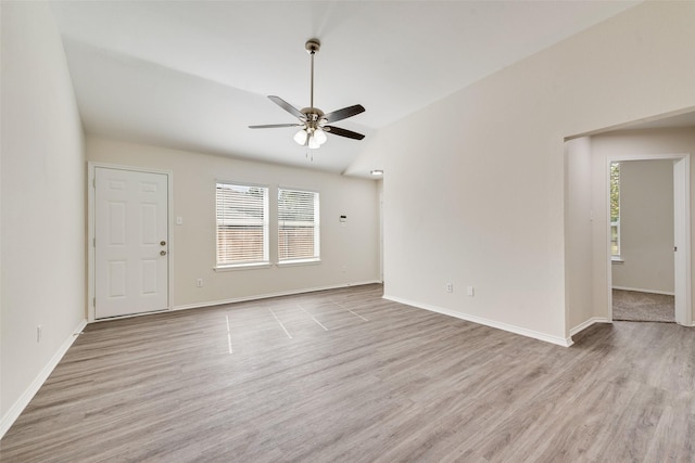 unfurnished room with lofted ceiling, ceiling fan, wood finished floors, and baseboards