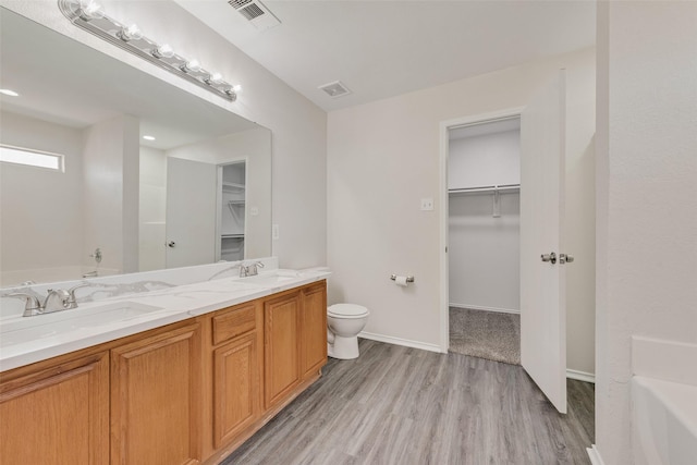 bathroom featuring a tub to relax in, visible vents, a sink, and wood finished floors